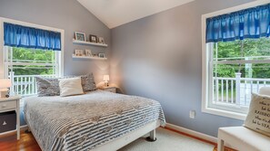 A bedroom with a bed, nightstands, a chair, and two windows with blue curtains. - Rapalee Retreat - Wine and Lake Lovers Take Notice! (Himrod)