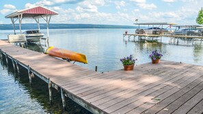 A wooden dock extending into calm water with boats docked, a covered seating area, and potted plants. - Rapalee Retreat - Wine and Lake Lovers Take Notice! (Himrod)