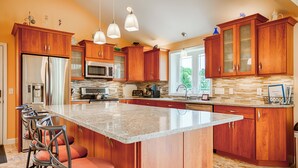 Una cocina moderna con armarios de madera, una isla grande, electrodomésticos de acero inoxidable e iluminación colgante.