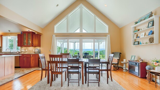 Una cocina amplia con un gran ventanal, armarios de madera y una zona de comedor con mesa y sillas.
