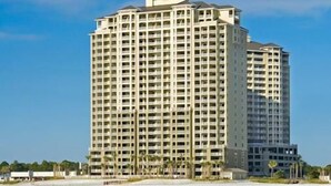 A multi-story hotel with a uniform exterior, located near a beach with palm trees. - Renovated with Gulf View Free Beach Chairs, Golf, & Activities Daily! (Panama City Beach)