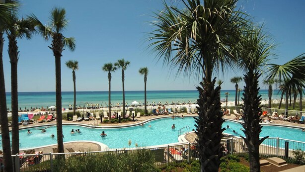 A pool area with palm trees, lounge chairs, and umbrellas. - Renovated with Gulf View Free Beach Chairs, Golf, & Activities Daily! (Panama City Beach)