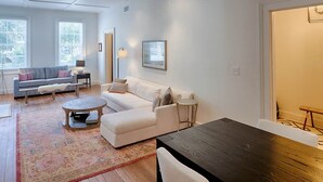 A modern living room with a sofa, coffee table, and a dining table. - Elegantly Appointed Washington Square Home, Close to River by Lucky Savannah (Savannah)