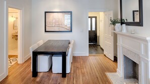 A modern dining area with a wooden table and white chairs, a framed map on the wall, and a fireplace. - Elegantly Appointed Washington Square Home, Close to River by Lucky Savannah (Savannah)
