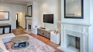 A modern living room with a fireplace, a flat-screen TV, and a large mirror. - Elegantly Appointed Washington Square Home, Close to River by Lucky Savannah (Savannah)