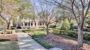 A pathway leading to a building with a symmetrical facade, surrounded by well-maintained landscaping and trees. - Elegantly Appointed Washington Square Home, Close to River by Lucky Savannah (Savannah)