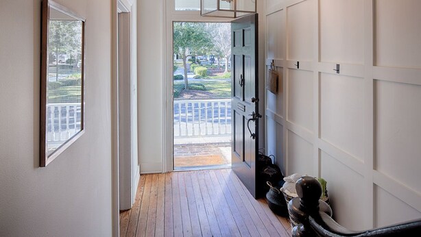 A hallway with a wooden floor, a door leading outside, and a wall-mounted light fixture. - Elegantly Appointed Washington Square Home, Close to River by Lucky Savannah (Savannah)