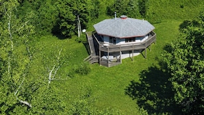 A house with a hexagonal roof, surrounded by lush greenery.