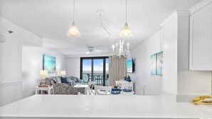 A modern kitchen with white cabinetry, a large island, pendant lighting, and a view to the outside. - Rate Reduced! Beachfront 2BR w/ Gulf Views, GOLF CART! Steps to Beach & Pool. (Destin)
