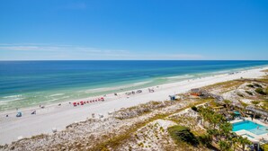 A beach resort with a swimming pool, beach umbrellas, and a lifeguard tower. - Rate Reduced! Beachfront 2BR w/ Gulf Views, GOLF CART! Steps to Beach & Pool. (Destin)
