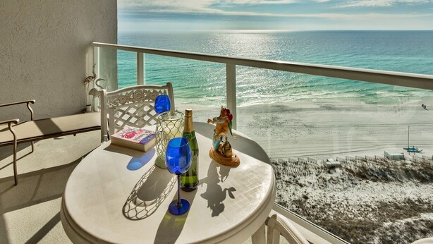Ein Balkon mit Tisch für zwei Personen, mit Blick auf einen Strand.