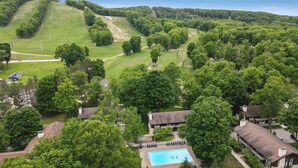 A residential area with a swimming pool, houses, and a large green park.