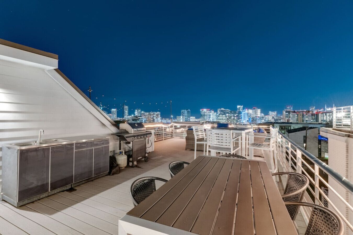 Eine Dachterrasse mit Blick auf den Stadtpanoramablick, Außenbestuhlung und einem Grill.