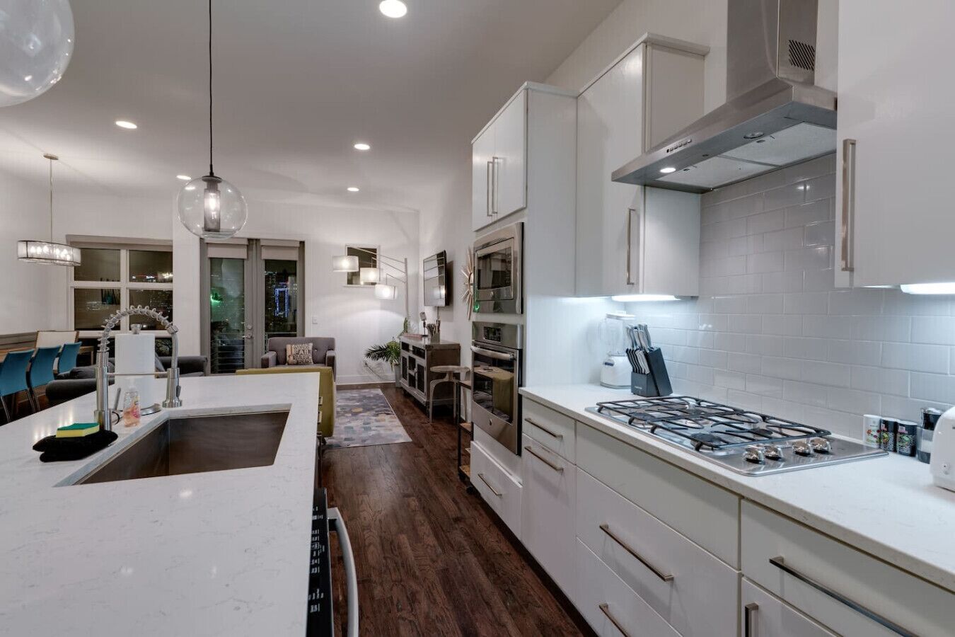 A modern kitchen with white cabinetry, a central island, a gas stove, and a built-in oven.
