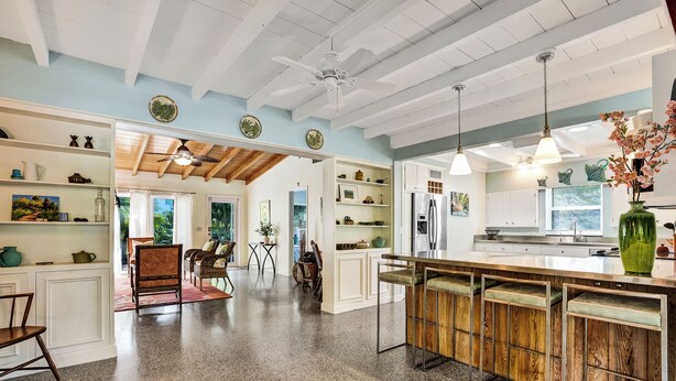 Una cocina amplia con una isla de madera, armarios blancos e iluminación colgante.