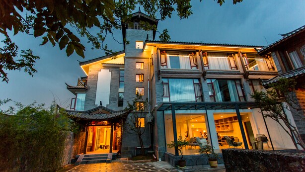 A traditional and modern two-story house with a large entrance, a balcony, and a well-lit interior. - Wangshan Travelling With Hotel (Lijiang)
