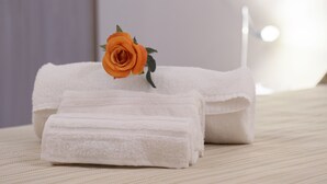 Neatly folded white towels and an orange rose on a textured surface. - Domus il Palio B&B (Siena)