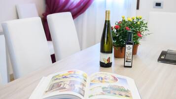 A table with an open book, a bottle of wine, and a bottle of olive oil.