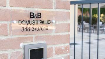 A brick wall with a sign for B&B Domus Il Palio, including a phone number.