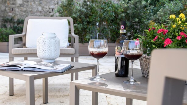 A table with two wine glasses, a bottle, and a book. - Domus il Palio B&B (Siena)