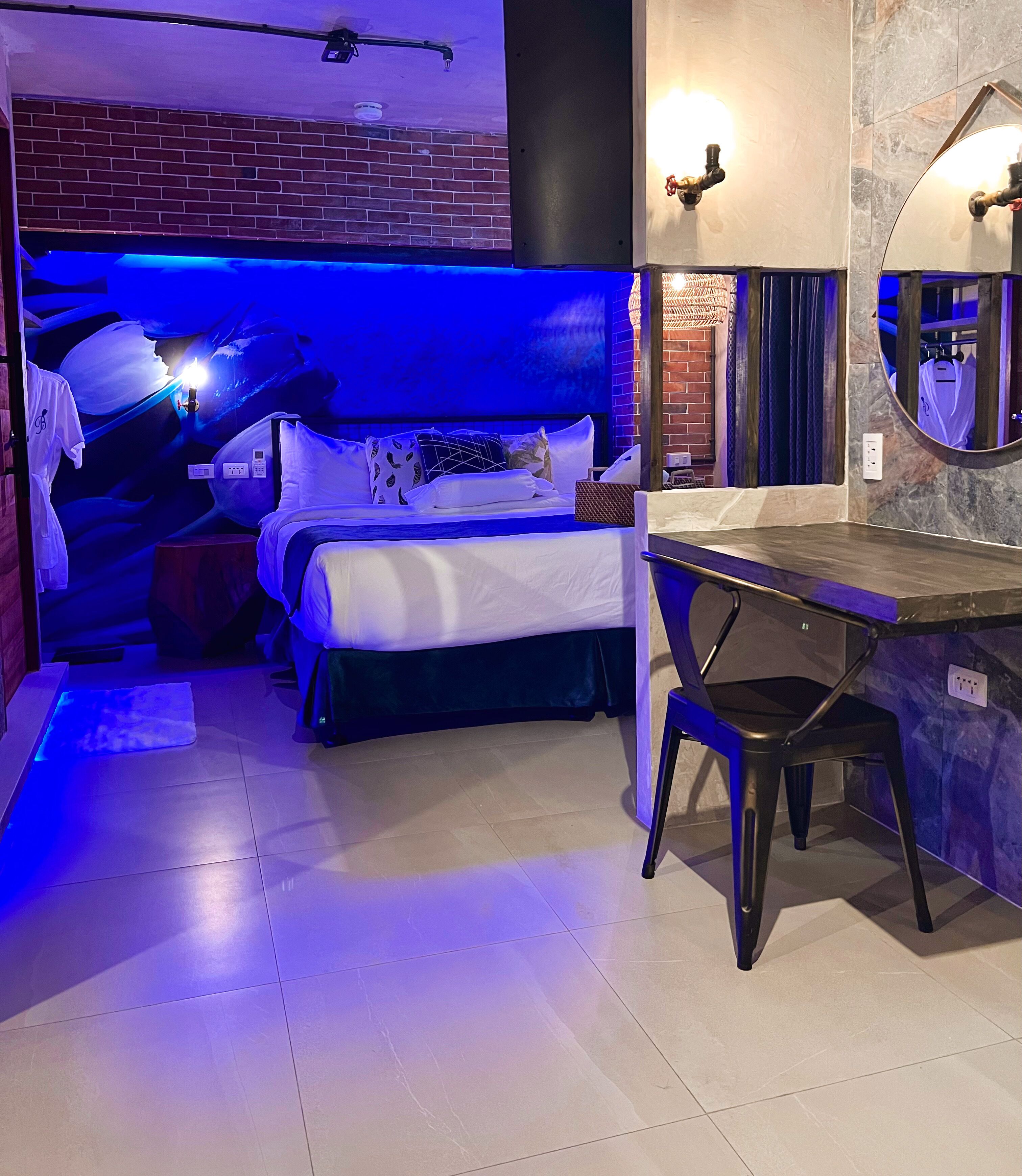 A bedroom with a bed, a desk, and a mirror.
