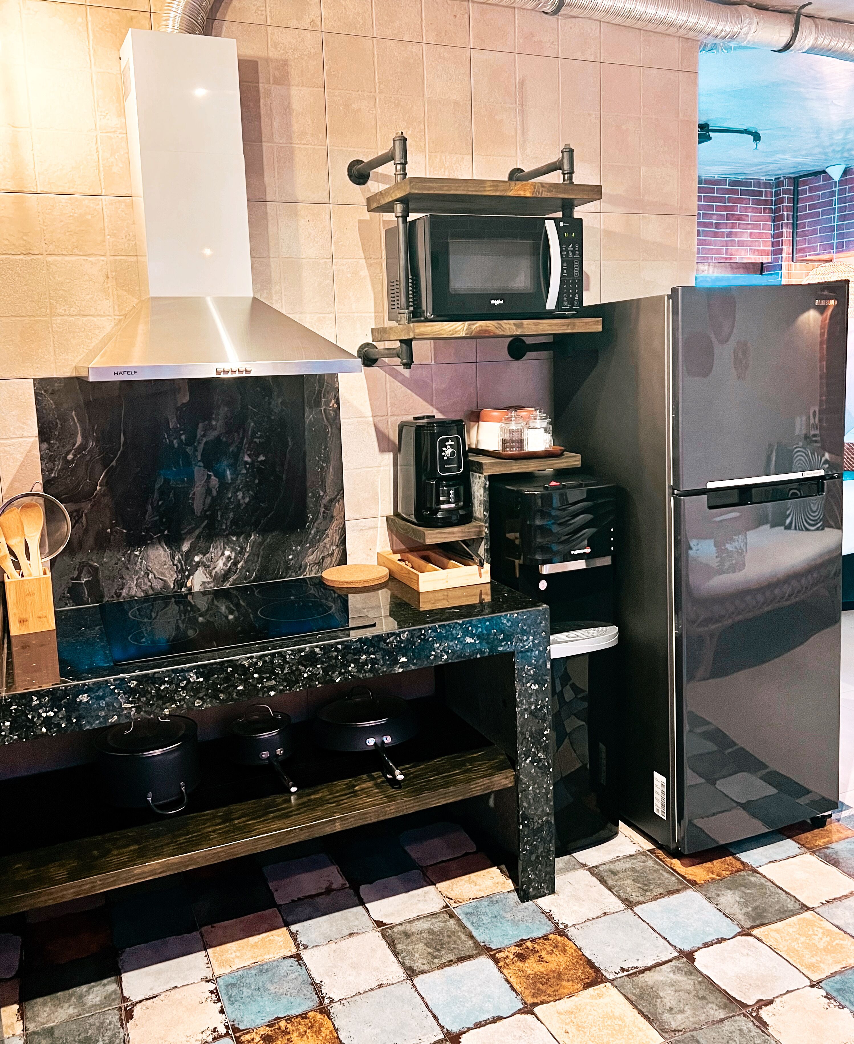 A kitchen with a black countertop, a microwave, a stove, and a refrigerator.