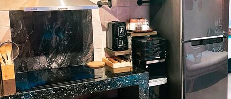 A kitchen with a black countertop, a microwave, a stove, and a refrigerator.
