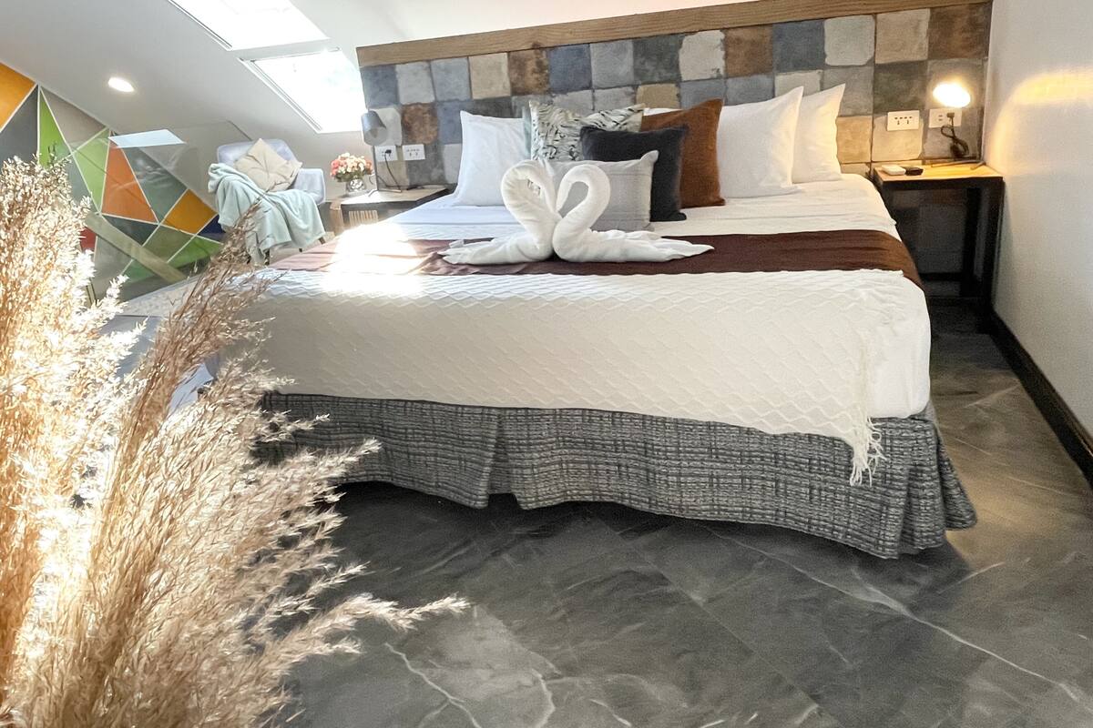 Un dormitorio moderno con una cama grande, cabecera de piedra y un tragaluz.
