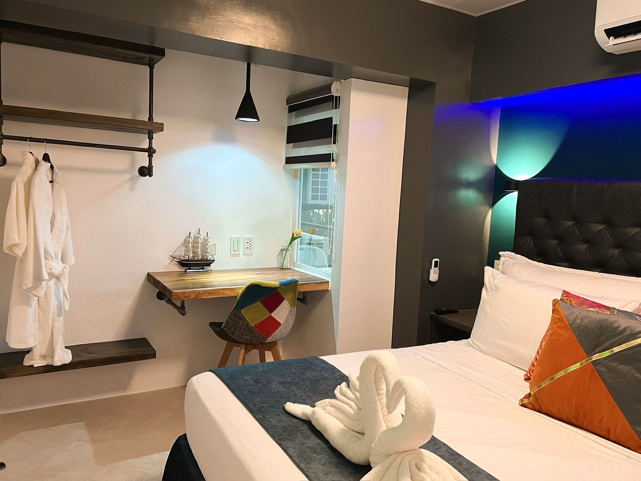 Una habitación de hotel moderna con cama, escritorio, silla y ventana.