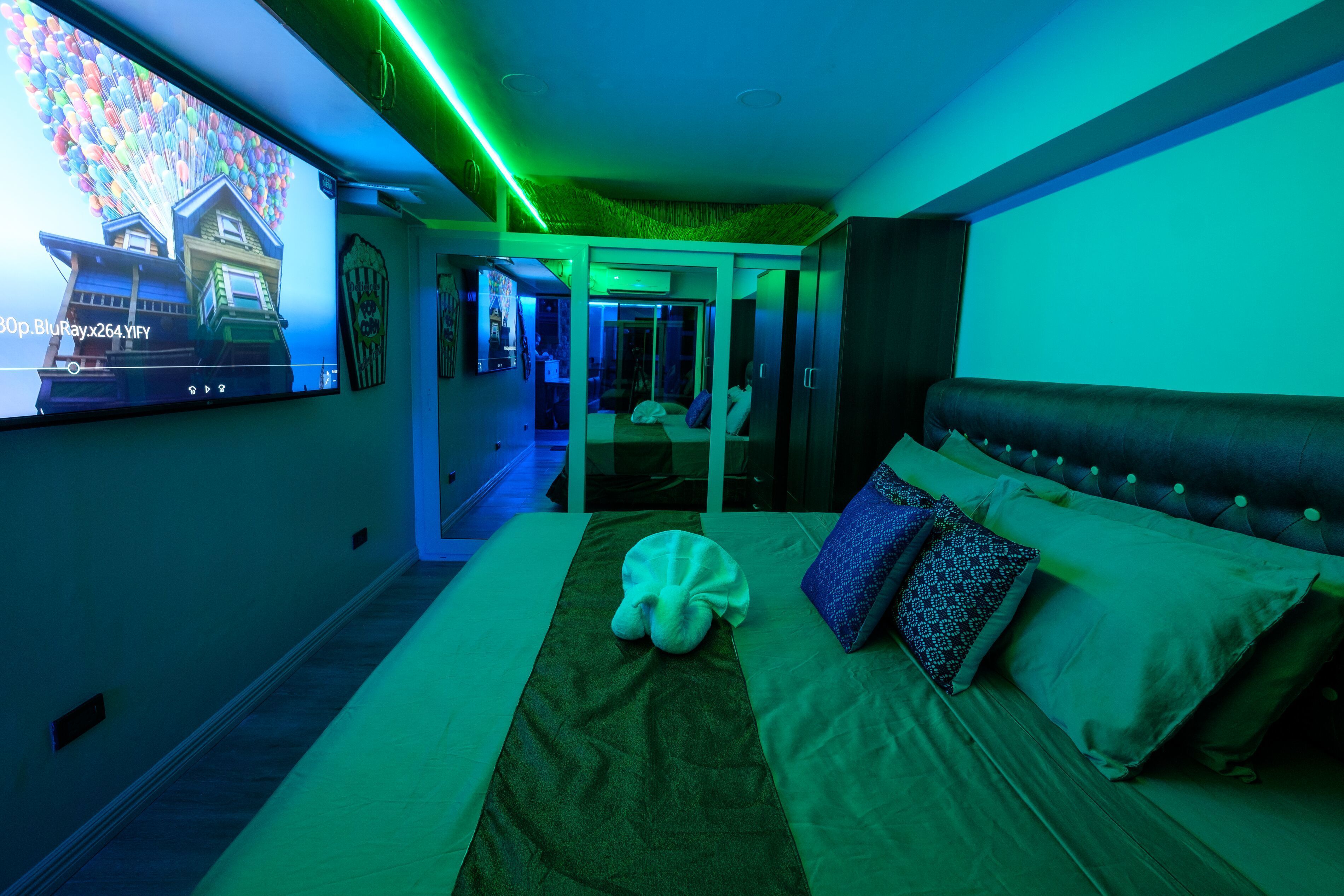 Una habitación de hotel moderna con una cama grande, un televisor de pantalla plana y una luz ambiental verde.