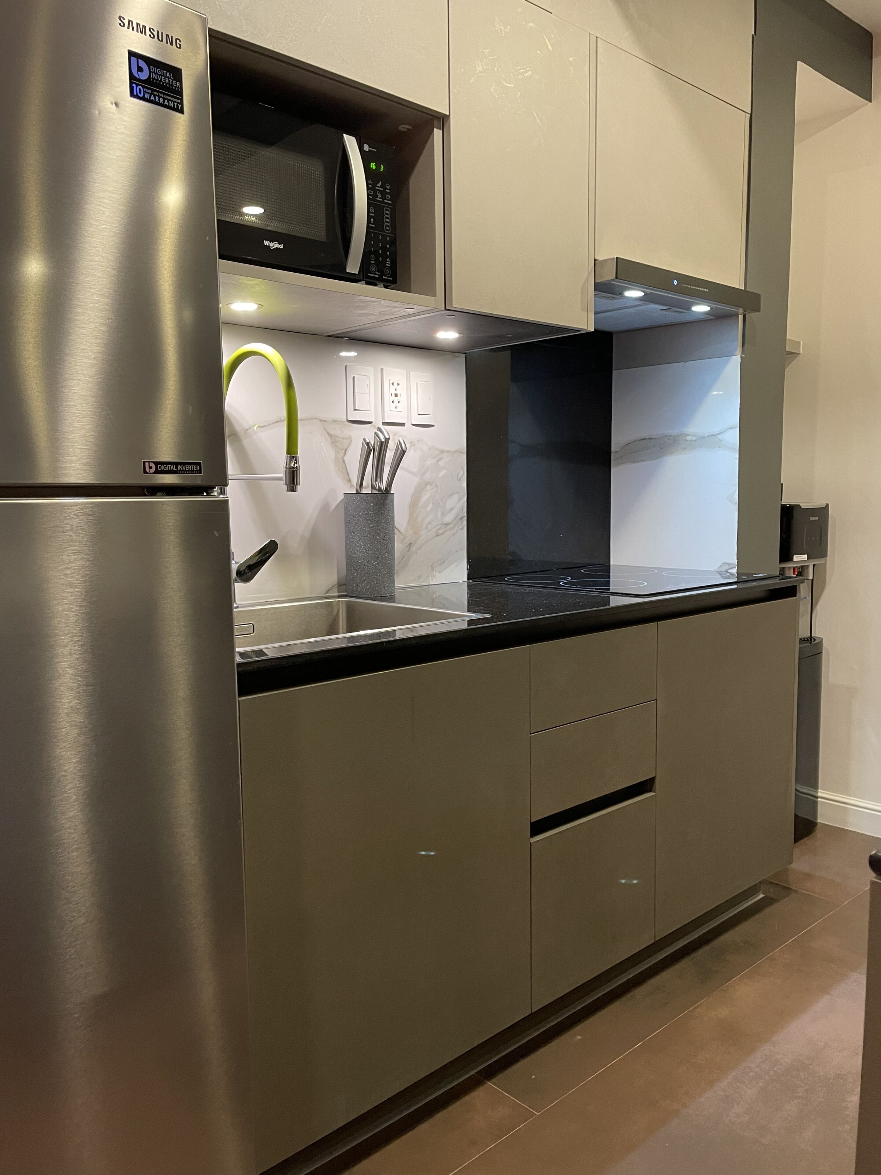 A modern kitchen with stainless steel appliances, a digital inverter refrigerator, and a sleek backsplash.