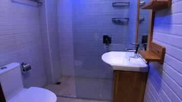 A bathroom with a toilet, a sink, and a shower area.
