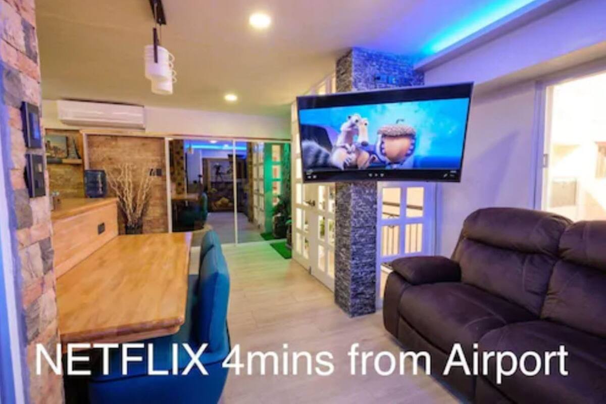 Una sala moderna con una televisión de pantalla plana, una mesa de comedor de madera y un sofá marrón.