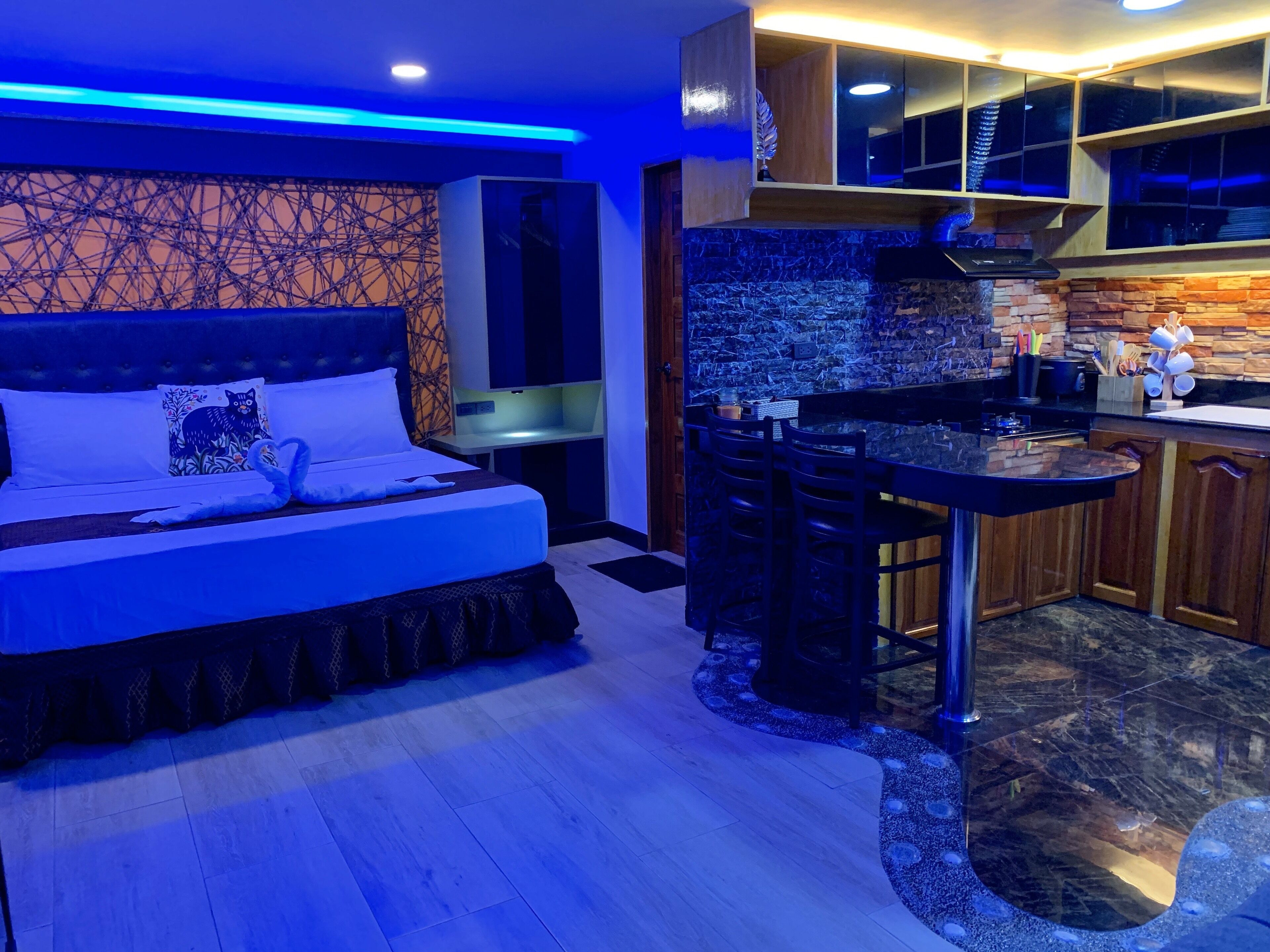Une chambre moderne avec un grand lit, une petite kitchenette et une salle de bain.