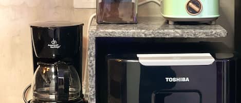 Una encimera de cocina con cafetera, tostadora y dispensador de agua.