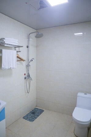 A bathroom with a shower, toilet, and a towel rack with folded towels. - Emeishan Hongzhao Hotel (Leshan)