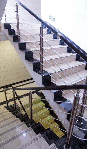 A staircase with black and beige steps, metal railings, and a patterned floor. - Emeishan Hongzhao Hotel (Leshan)