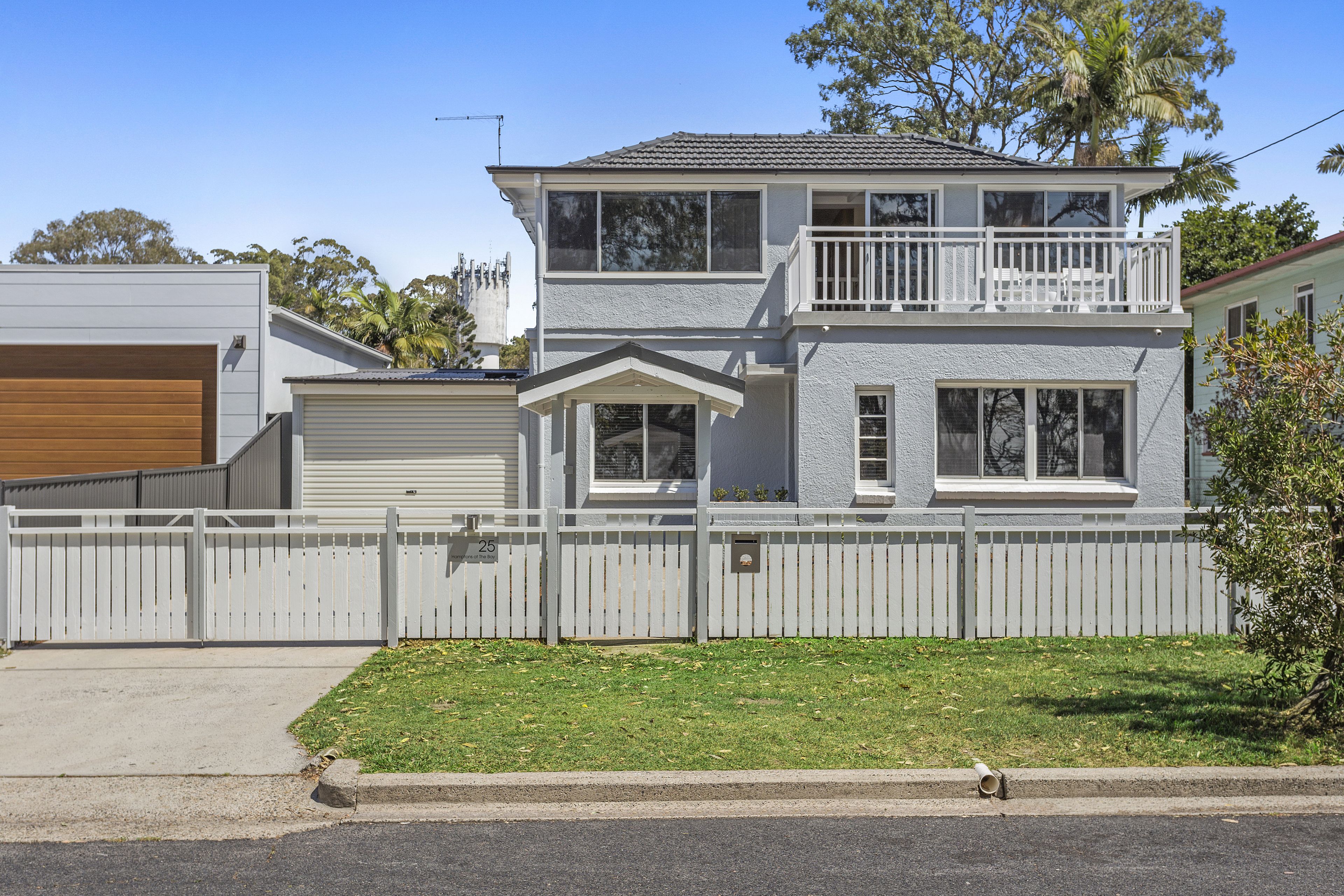 A two-story house with a white exterior, a front porch, and a fenced yard.