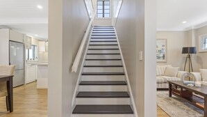 A modern staircase in a residential interior, leading to a kitchen and living area. - Hamptons at The Bay (Deception Bay)