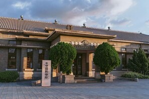 A building with a tiled roof, a central entrance, and two symmetrical trees in front. - K.GOLD HOSTEL (Taichung)
