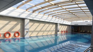 An indoor swimming pool with clear glass walls, a tiled floor, and orange life rings on the wall. - Menshine Gloria Plaza Hotel Shantou (Shantou)