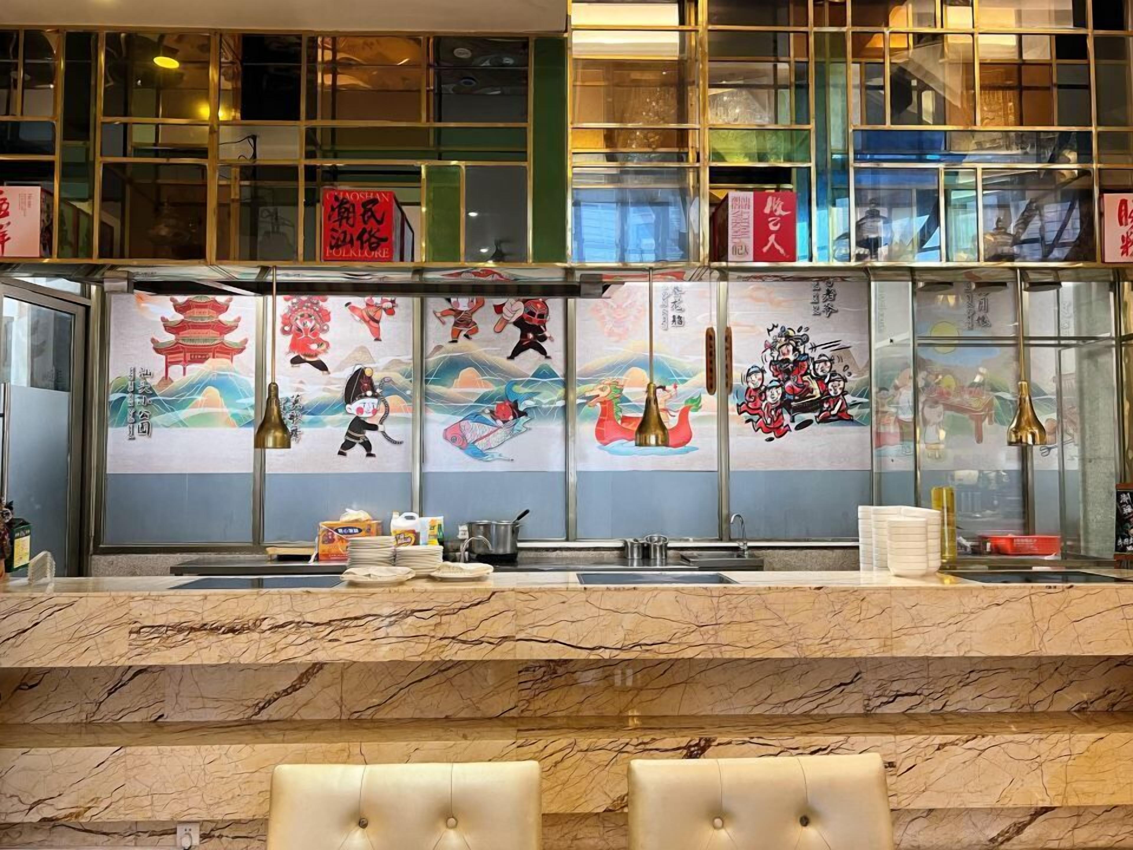 Un interior de restaurante con una encimera de mármol, obras de arte tradicionales en la pared y un separador de vidrio.