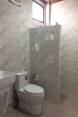 A bathroom with a toilet, a shower enclosure, and a sink. - Tai Baan Resort (Phanom Sarakham)