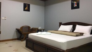 A bedroom with a wooden bed, a small wooden desk, and two framed pictures on the walls. - Tai Baan Resort (Phanom Sarakham)