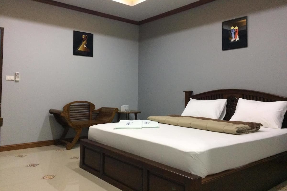 A bedroom with a wooden bed, a small wooden desk, and two framed pictures on the walls.