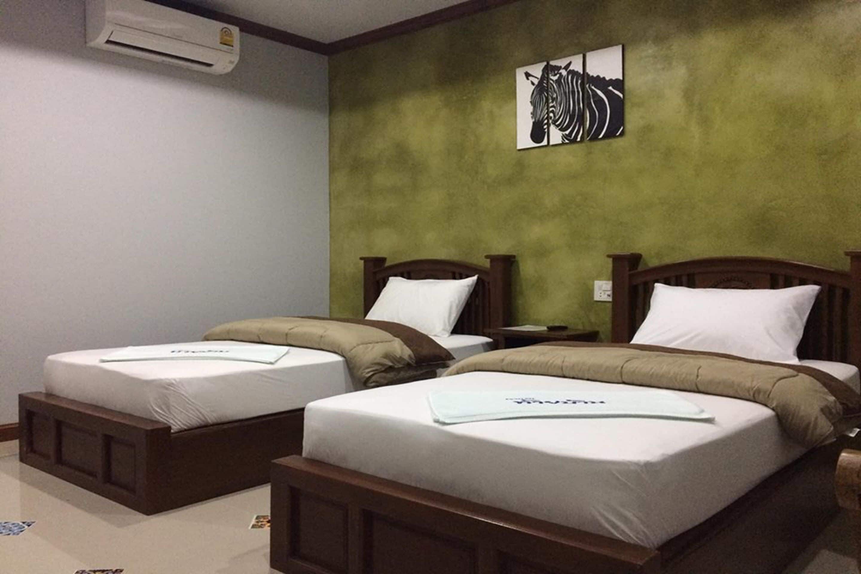 Two single beds with wooden headboards and white bedding in a room with green walls.
