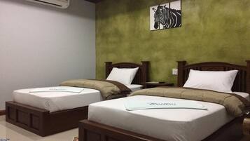Two single beds with wooden headboards and white bedding in a room with green walls.