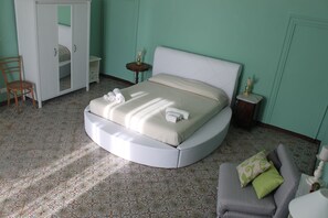 Un dormitorio con una cama redonda, un armario, una silla, una mesita de noche y una lámpara.