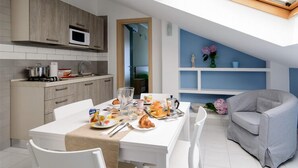 A modern kitchen with a dining area, white cabinetry, and a breakfast setup. - Greco BeB (Agropoli)