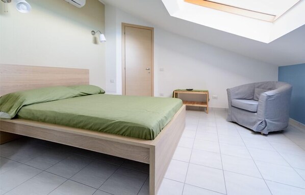 A bedroom with a bed, a chair, a nightstand, and a skylight. - Greco BeB (Agropoli)